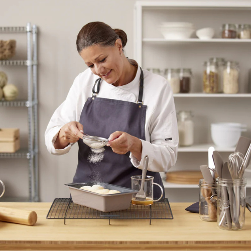 Chef Jane gently dusting powdered sugar onto homemade bread dough in a bright, organized kitchen.